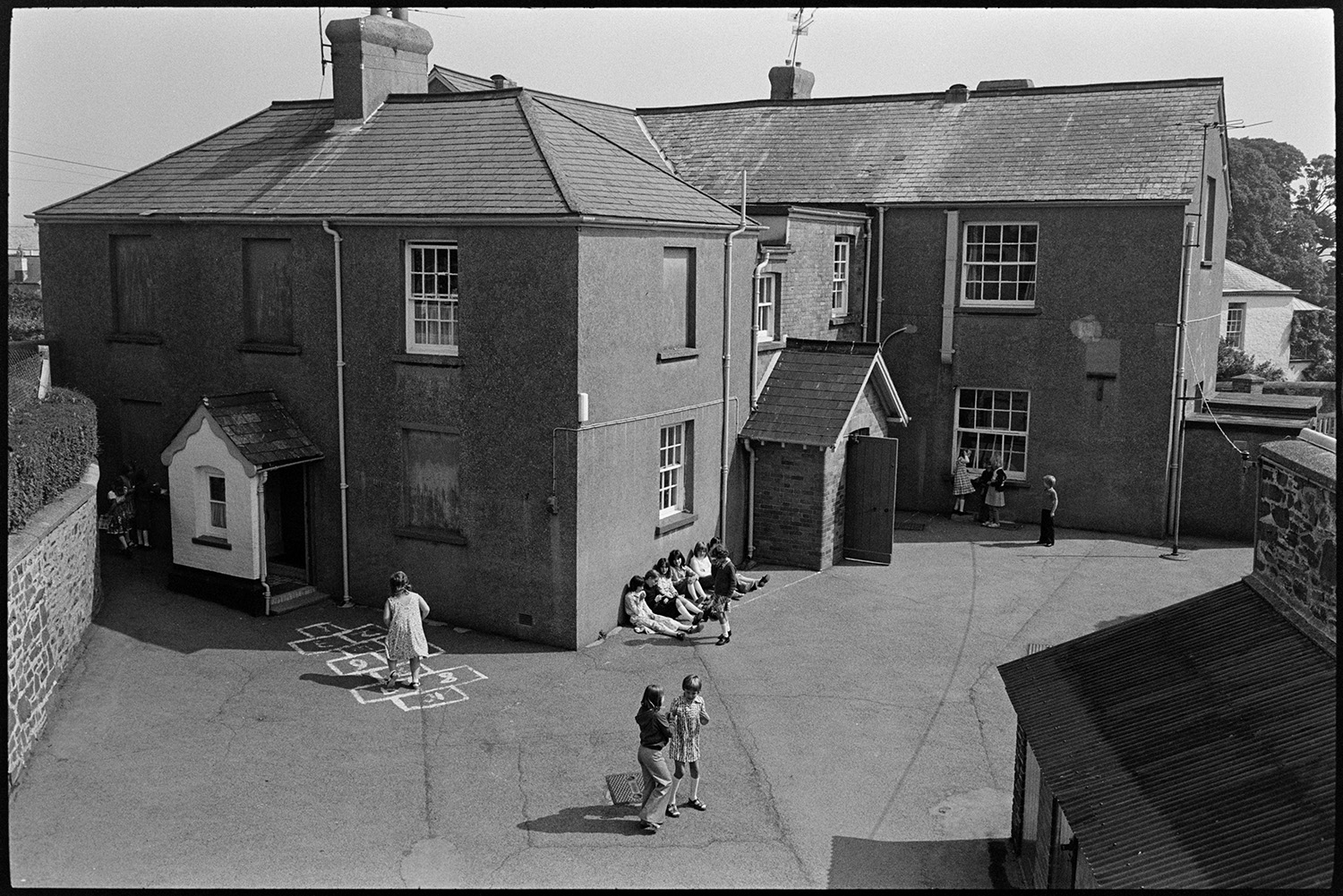 Children at break time, having free milk and playing outside. 
[Children playing in the playground at Blue Coats School in Torrington at break time. One girl is playing on the hopscotch.]