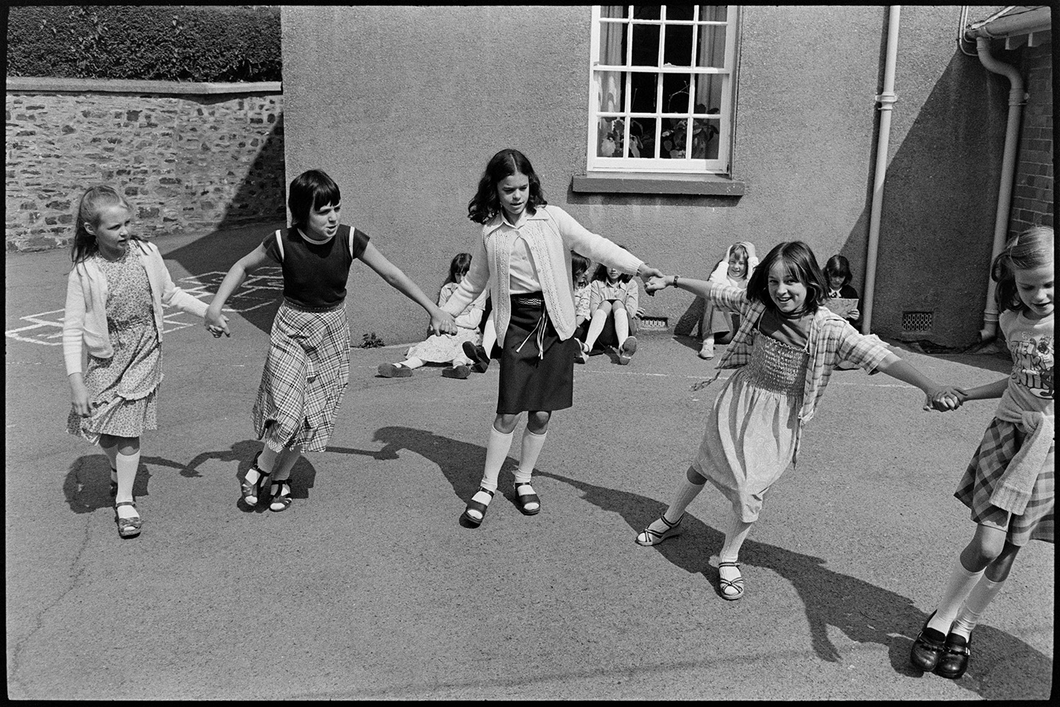 Children at break time, having free milk and playing outside. 
[A group of girls playing in the playground at Blue Coats School in Torrington at break time. They are holding hands and running.]