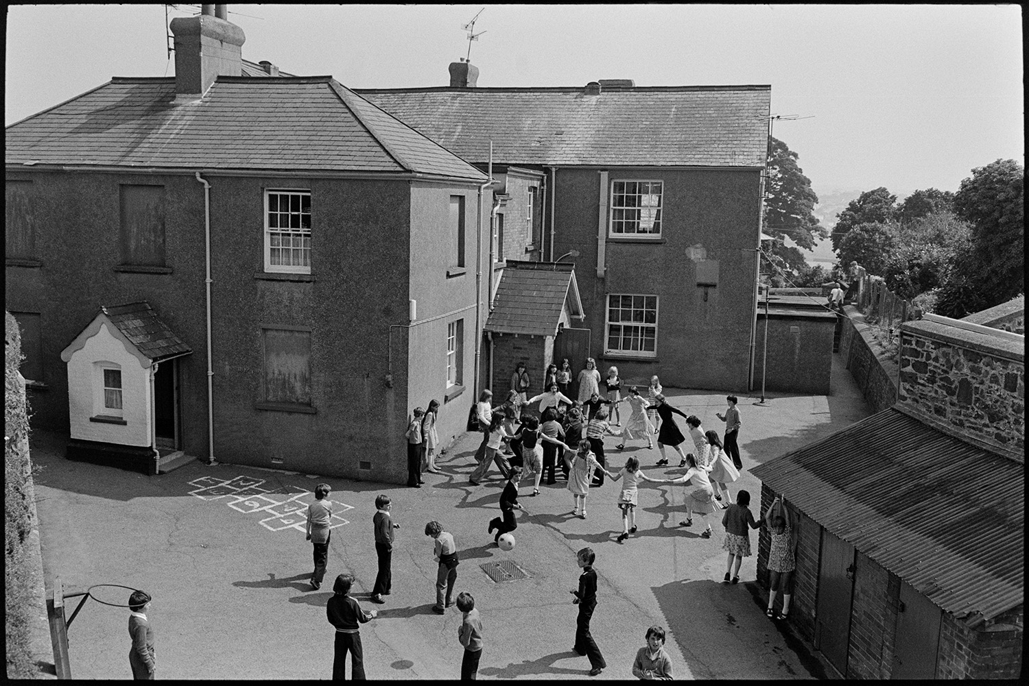 Children at break time, having free milk and playing outside. 
[Children playing in the playground at Blue Coats School in Torrington at break time. Some of the children are playing football while others are holding hands in a circle and dancing round.]