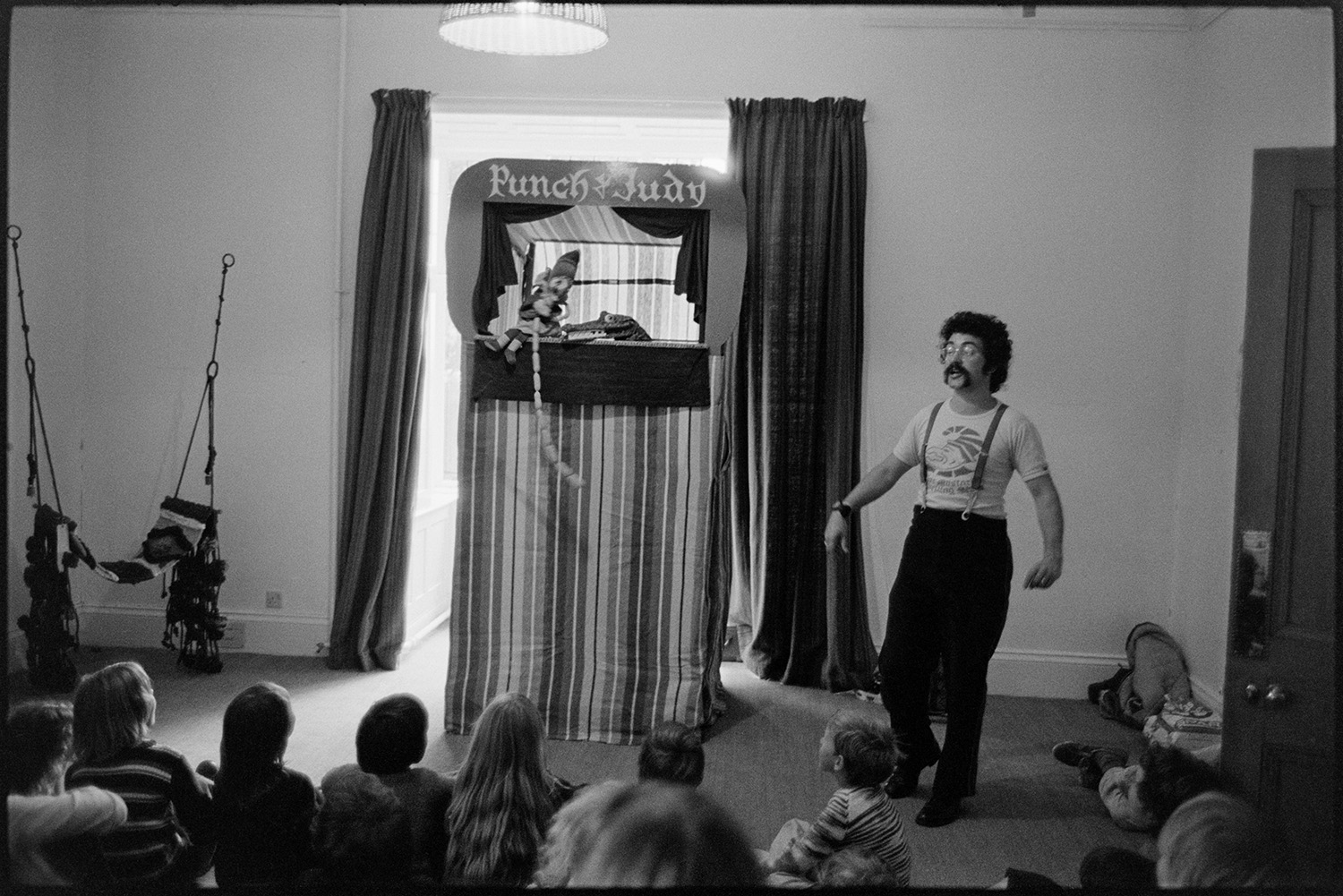 Children on course, playing with sculpture, Punch & Judy show. 
[Children watching a man delivering a Punch & Judy show in a room at The Beaford Centre at Greenwarren House, Beaford.]