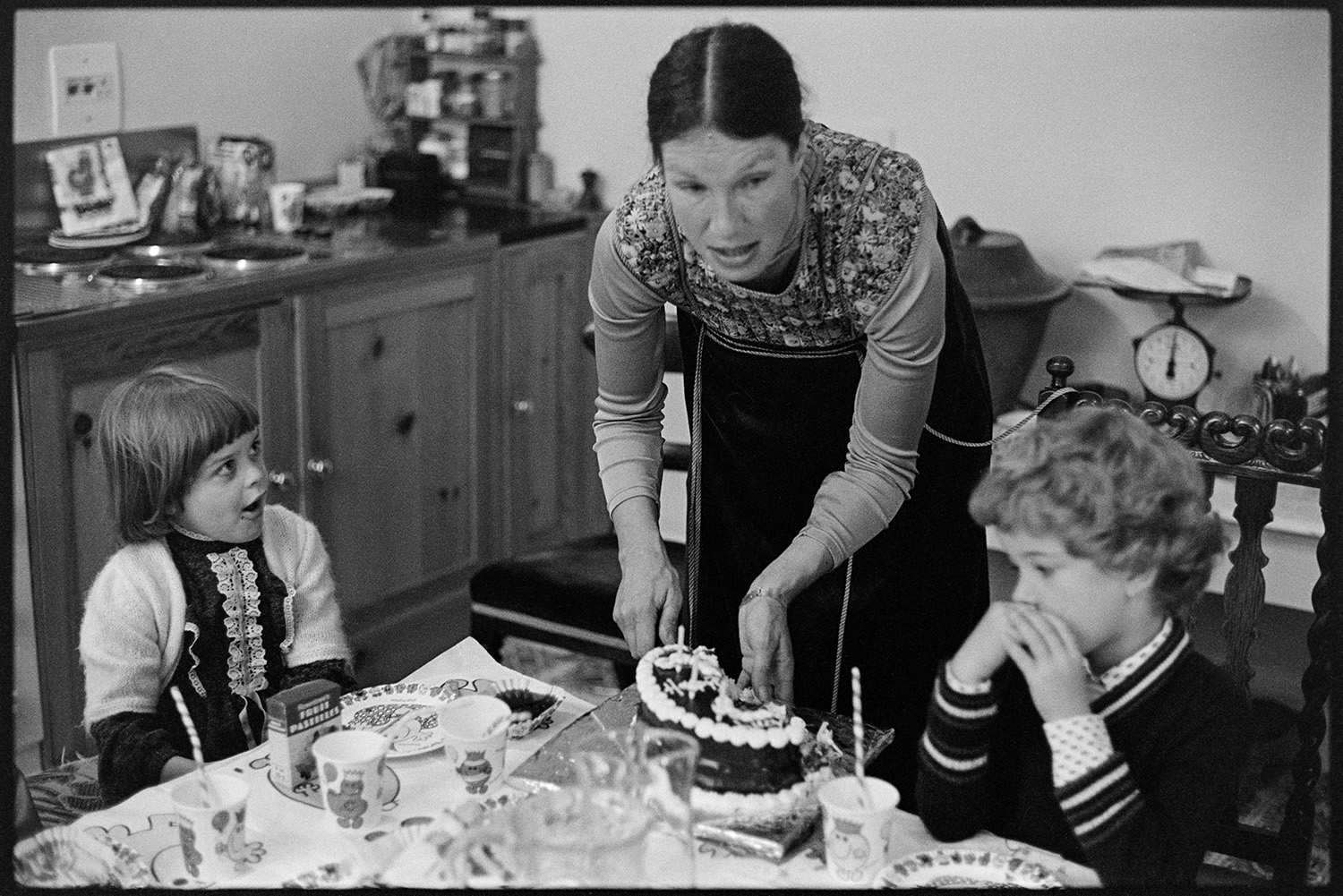 Birthday tea, mother cutting cake handing it round. 
[Hilary Hill cutting the cake at her child's 6th birthday party at Marwood House. She is handing the cake round to the other children.]
