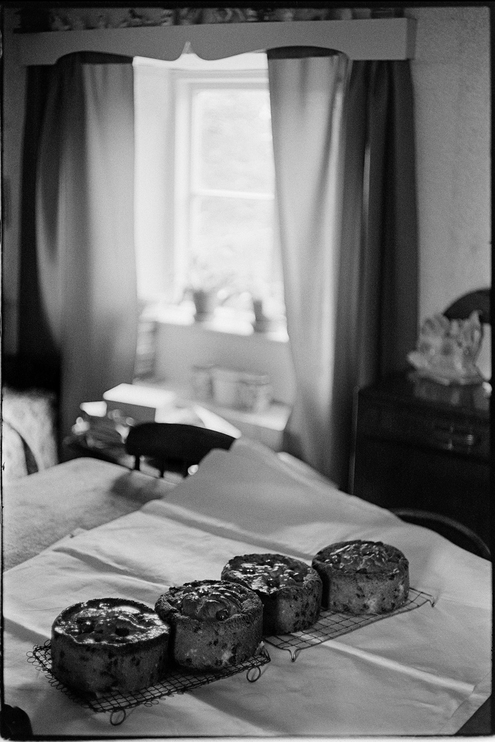 Woman baking cakes for WI market stall. 
[Four fruit cakes baked by Rene Ware cooling on wire racks in a house at Reynards Park, Ashreigney. They are going to be sold on a Women's Institute market stall.]
