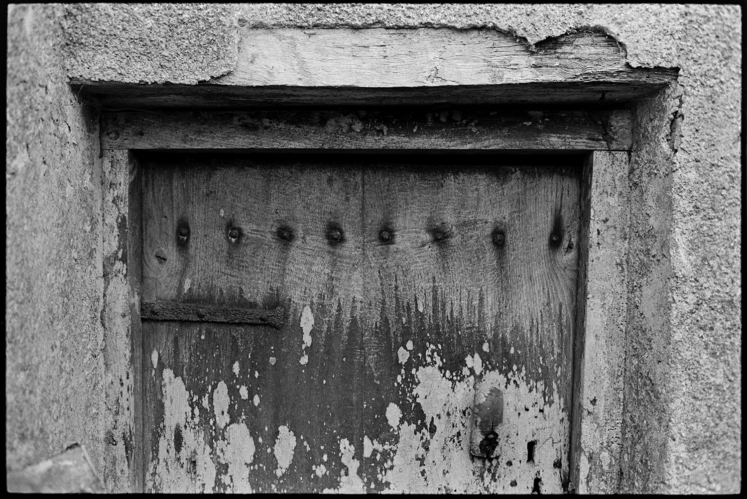Ancient door and remains of barn window with carved frame. 
[A wooden door of an old barn in Monkokehampton.]
