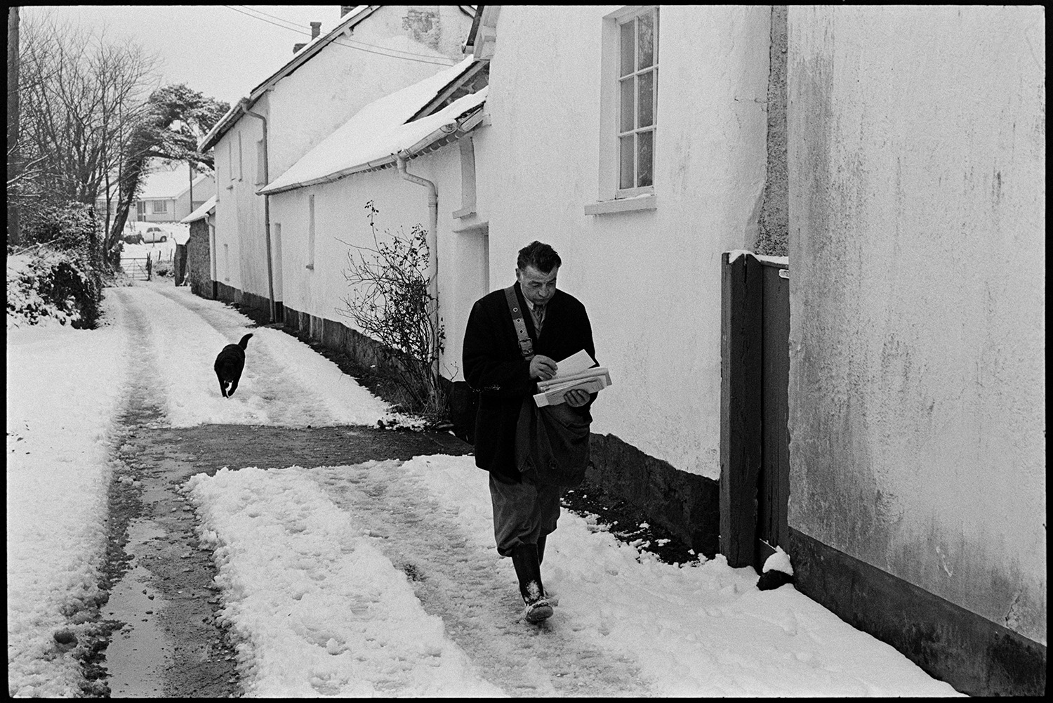 Snow, Street scenes postman and dog, children throwing snowballs, people chatting. 
[Harold Nott, also known as Joe Bec, a postman, walking along a snowy street in Dolton. He is accompanied by a dog and is carrying a handful of letters to deliver.]
