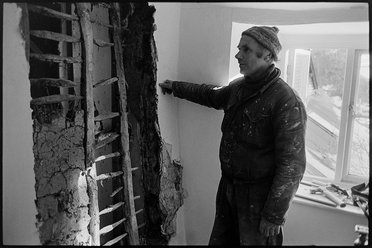 Old lathe and plaster wall with unusual timber work. 
[Derek Marden looking at a wall with exposed timber work and plaster, at a house called Merrymeet, Dolton.]